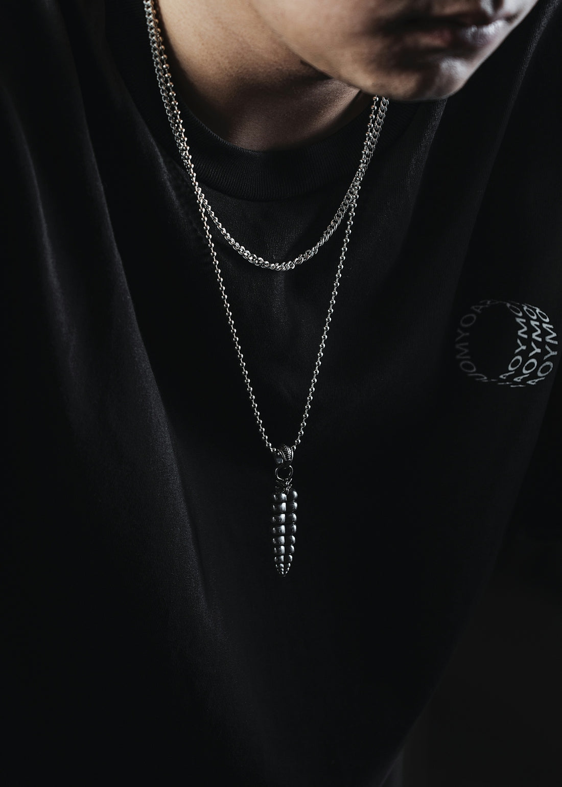a man wearing a black shirt and a silver necklace