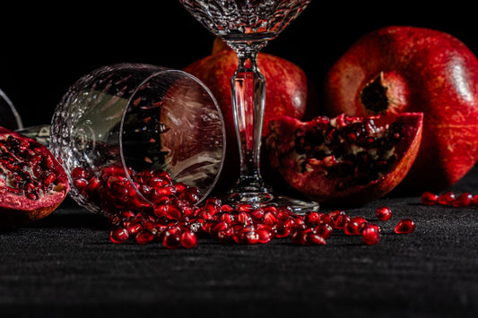 A table topped with a wine glass next to a pile of pomegranate