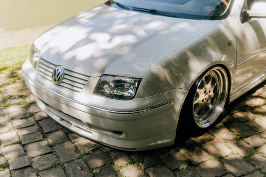 A silver volkswagen car is parked in the sunlight.