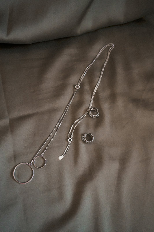 silver necklace on white textile