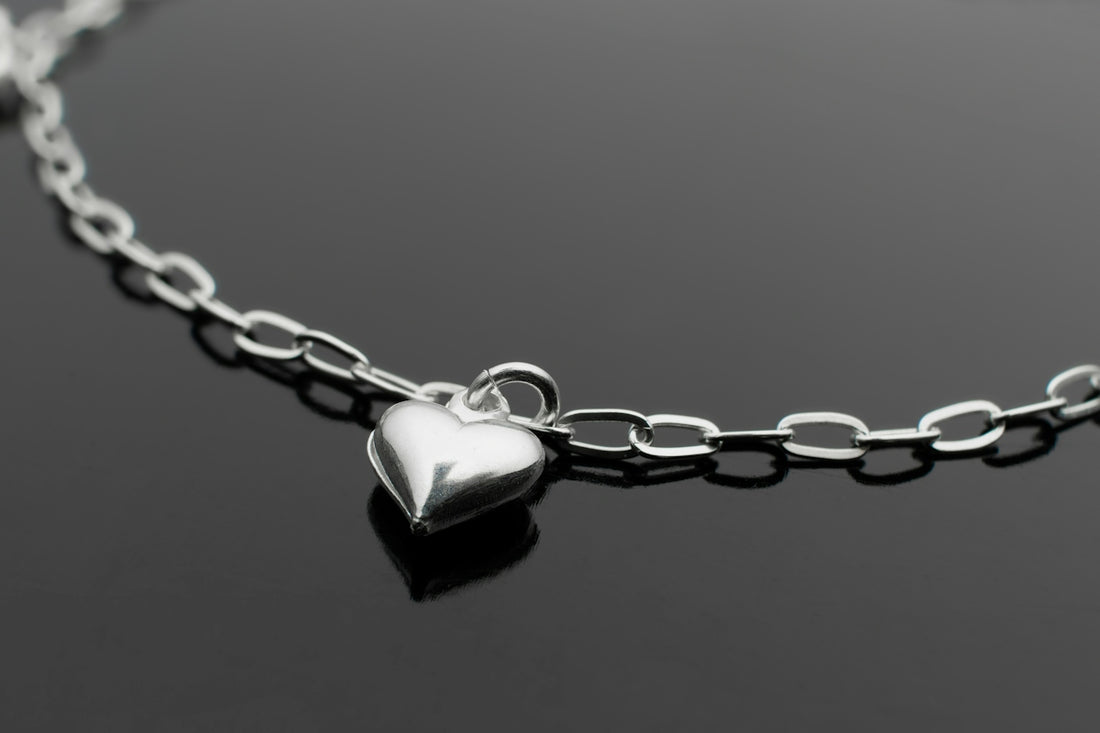a silver heart necklace on a black surface