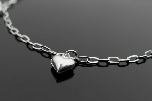 a silver heart necklace on a black surface