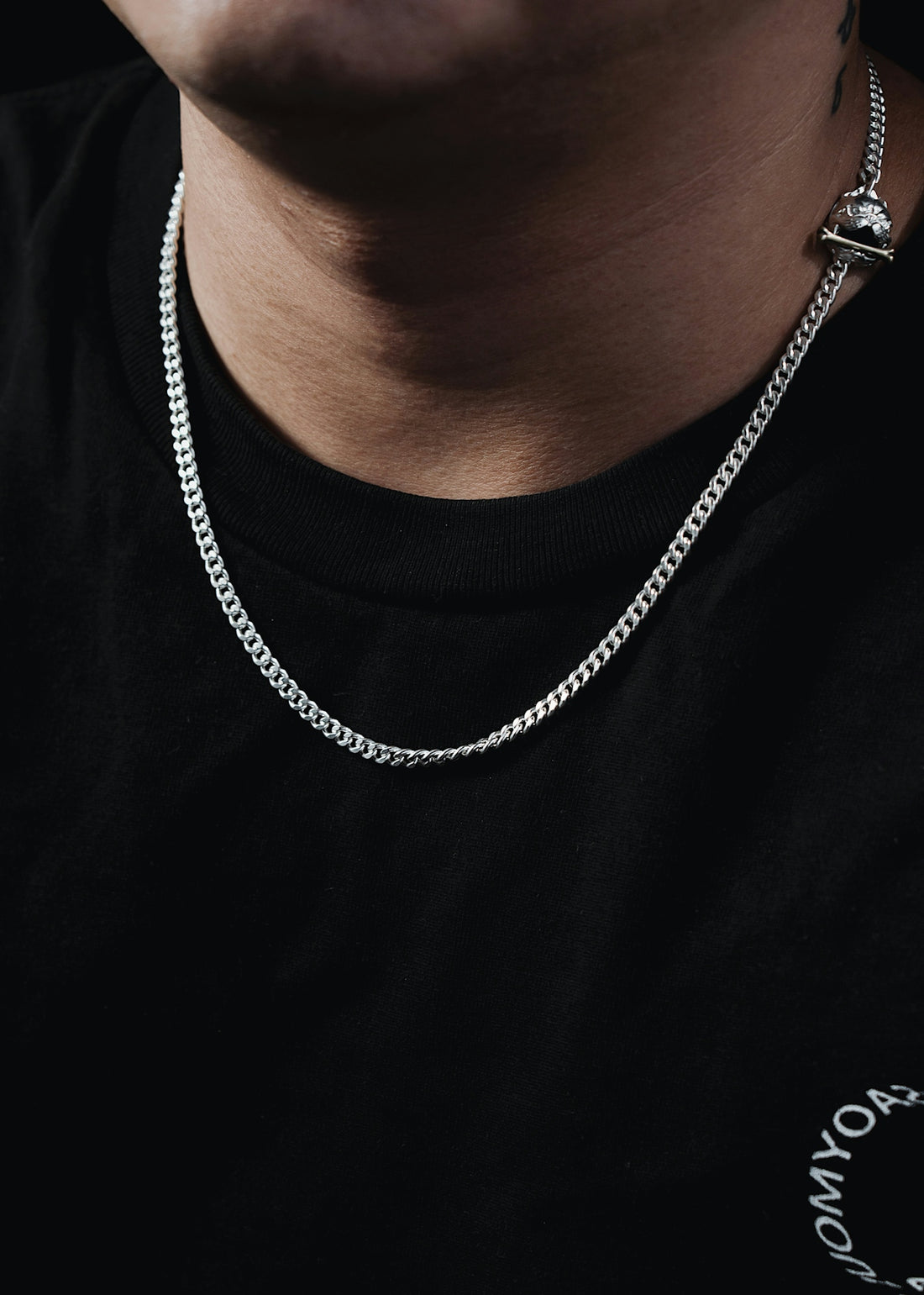 a man wearing a black shirt and a silver chain
