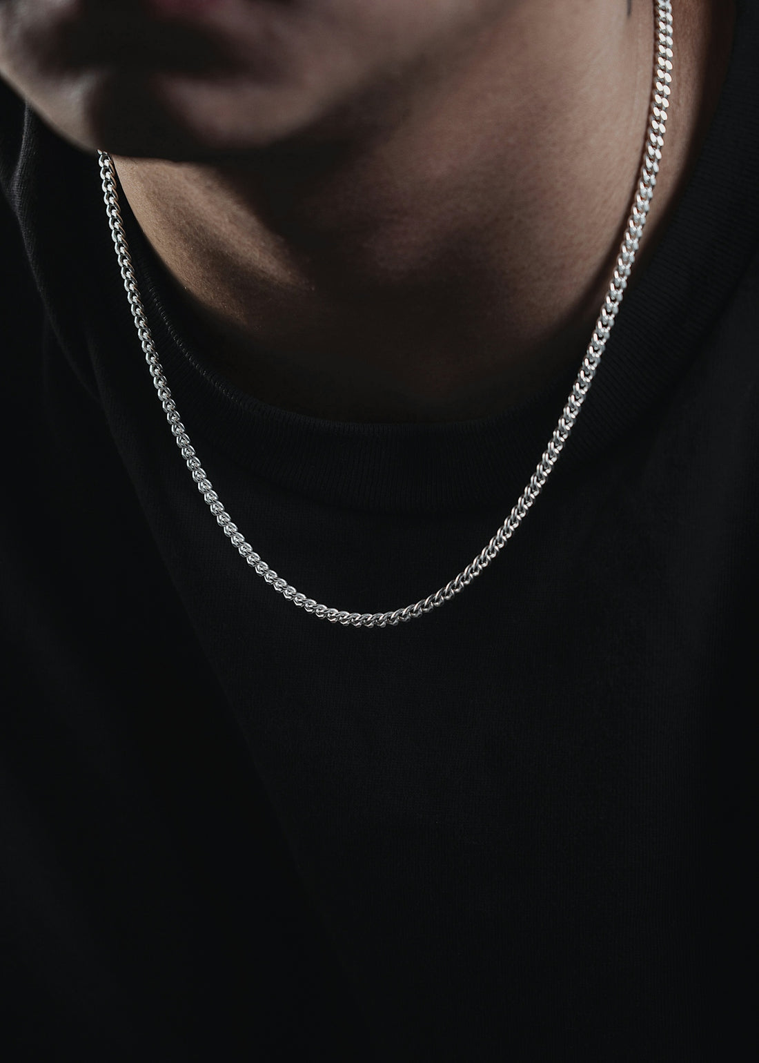 a man wearing a black shirt and a silver chain